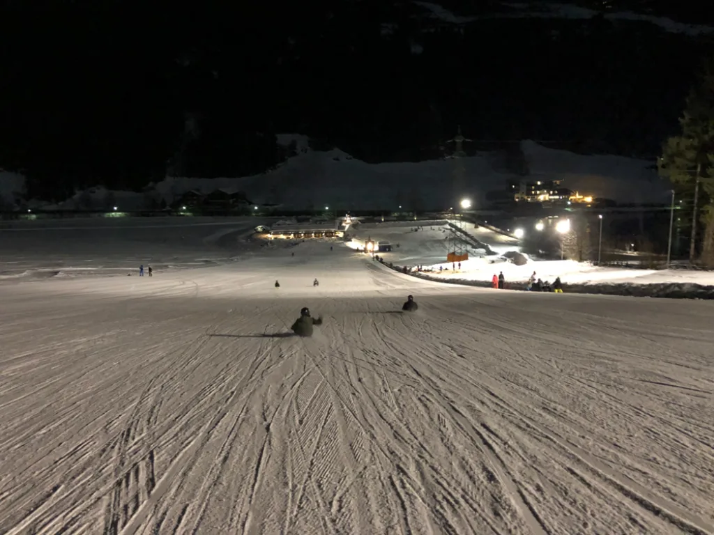 Blick über die beleuchtete Rodelbahn bei Nacht.